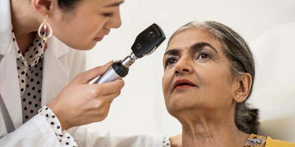 Eine Augenärztin untersucht eine ältere Patientin mit  feuchter altersabhängiger Makuladegeneration.
